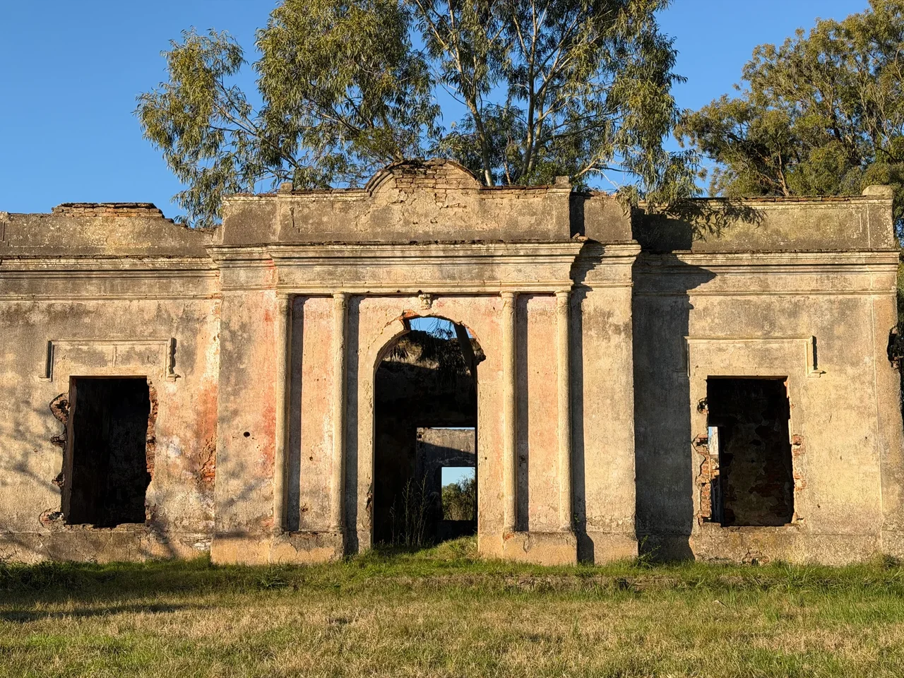 Fachada en ruinas de la antigua Aduana de Paso Centurión, rodeada de campo y árboles.